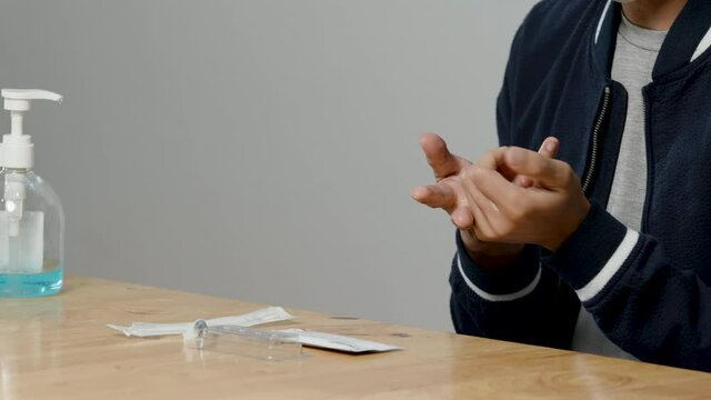 4K, Close Up Asian man's hands cleaning with alcohol gel before the test a rapid antigen test kit to self-test the COVID-19 epidemic at home