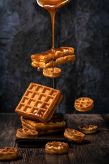 Belgian waffles with caramel syrup on a dark background. food is levitation. belgian waffles levitation