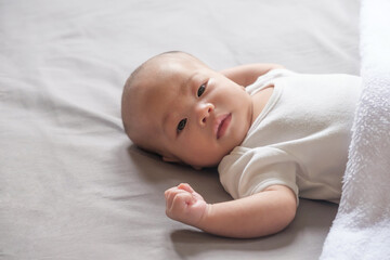 asian baby wear white shirt sleeping on gray bed