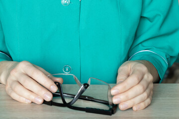 woman doctor holds in hands protective medical glasses at the desks in the doctor's office