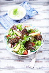 Salad with Grilled Beef Pieces, Cherry Tomatoes, feta Cheese and Kalamata Olives. Bright wooden background. 