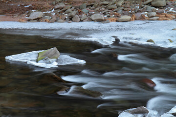 Mountain stream in winter with veiled water and ice