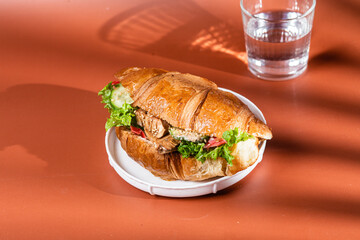 Croissant with terriyaki chicken on a white plate