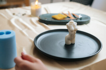 Close-up of unrecognizable female artisan putting on table ready to use handmade candle in shape of...