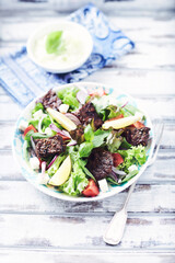 Salad with Grilled Beef Pieces, Cherry Tomatoes, feta Cheese and Kalamata Olives. Bright wooden background. 