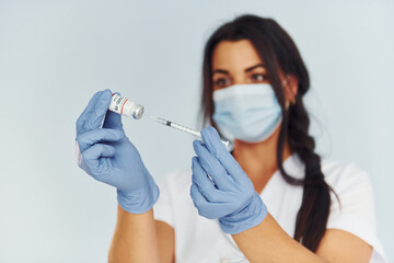 Holding test tube. Young female doctor in uniform is indoors