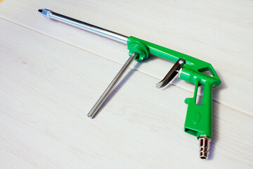 Green air compressor gun. Isolated on a wooden background