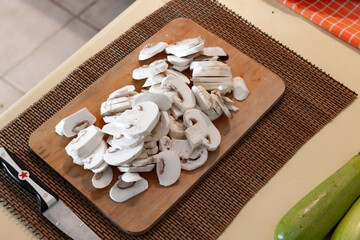 Chopped, cut mushrooms on wooden chopping board. Mise en place. House kitchen.  