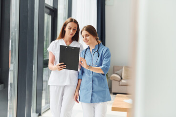 With documents. Two doctors in uniform standing indoors and working together