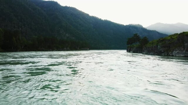 Flying over the water at high speed against the backdrop of a mountain landscape. The river is located between mountain passes.