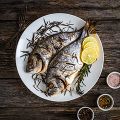 Roast sea bream with rosemary and lemon on wooden table
