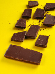 Broken milk chocolate bar. On yellow isolate.