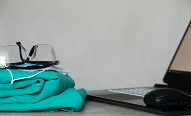 a medical suit and glasses lie near a laptop on the table, a doctor's office, medicine, medical