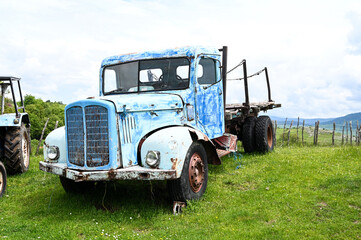 Rusty old truck on meadow. Abandoned blue car in nature. Vintage farm truck on the field.