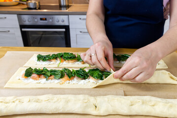 the cook puts spinach and trout on the dough. Savory Christmas pie in the shape of a wreath cooking process. close up