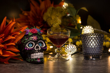 Day of the dead skull with red wine, flowers and lights