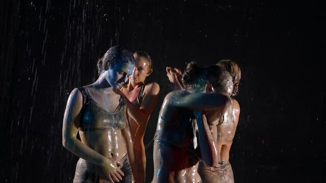 sexy ladies are dancing in rain in night, washing off paints from bodies, dancers in water flows