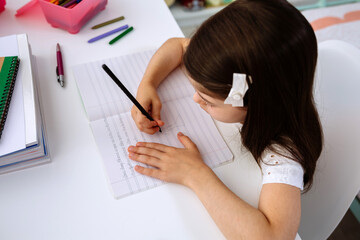Top view of girl doing homework sitting at a desk