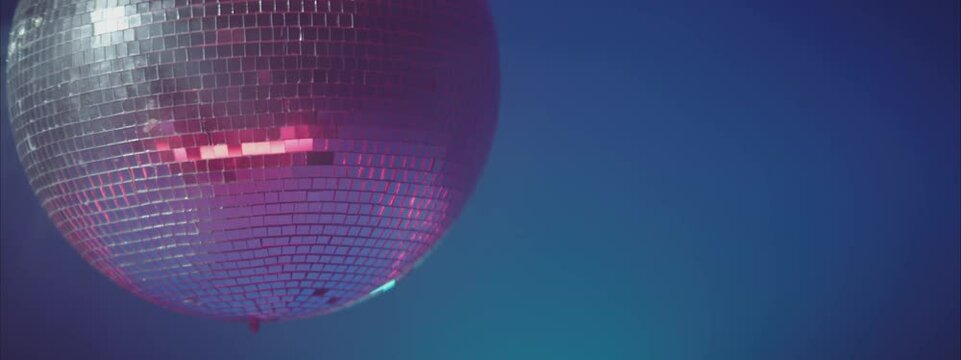 Silver disco ball against blue. Slowly rotating mirror sphere. Night party in club, music and entertainment concept.