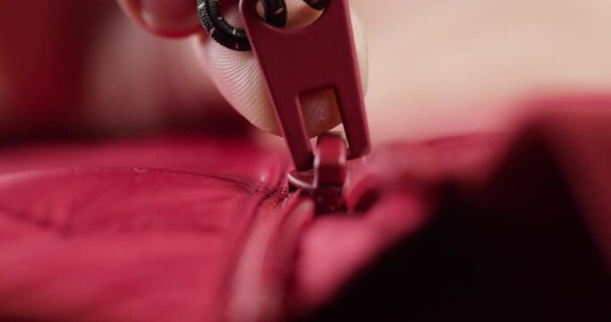 Hand zipping up red clothes close-up. Tailoring and sewing concept. Handmade things, dressmaking, macro shooting of textile sample.