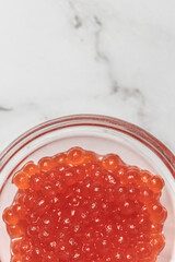 Red caviar in jar on white background. Gourmet food, appetizer, selective focus, place for text