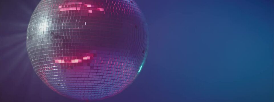 Rotating silver disco ball. Mirror sphere reflecting lights. Night party in club, music and entertainment concept.