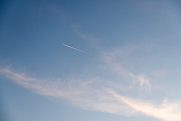 Airplane contrasting with sky at sunset. Airplane tracks over blue sky
