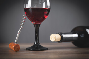 Bottle of red wine with glass and corkscrew.