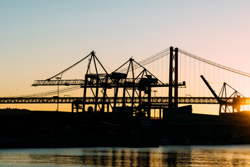Silhouette of cranes at the Port of Lisbon, Portugal with 25 April Bridge in background
