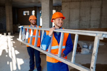 Construction builder workers carrying steel ladder together