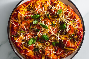 vegan homemade pizza with cherry tomatoes olives and fresh herbs topped with dairy-free cheese, healthy plant-based food