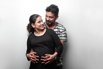Loving and caring husband of Indian ethnicity touches the tummy of his wife expecting a baby