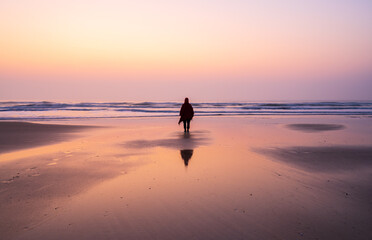 one person standing on the the beach in sunrise