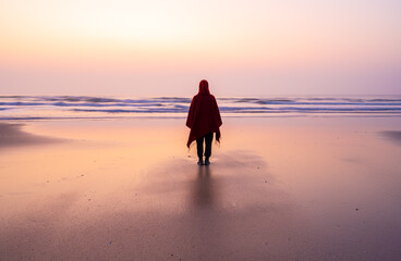 one person standing on the the beach in sunrise