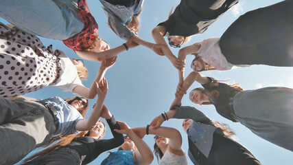A group of girls makes a circle shape holding each other's hands.
