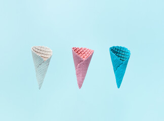 Colorful wafer cones against sky blue background. Summer holidays minimal concept. Popular ice cream flavors. 