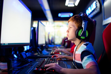 Caucasian boy gamer playing video games with friends on computer in game room. Children's addiction to virtual games and entertainment.