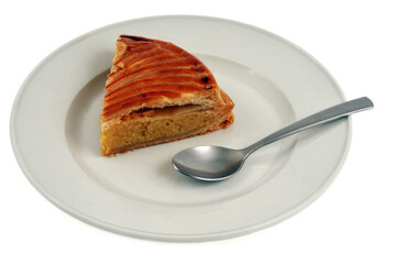 Part de Galette des rois dans une assiette avec une cuillère en gros plan sur fond blanc
