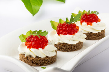 Smorrebrod. Luxurious delicacies spotlighting red caviar and avocado garnish on a rye base, presented on a pristine white plate, embodying culinary sophistication.