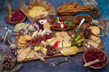 Cheese and crackers board with fruit and pickles on wooden board