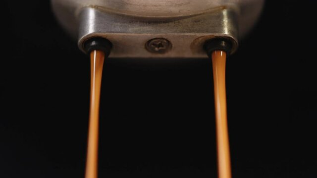 Close up making espresso Flowing fresh ground coffee. Pouring coffee stream from professional machine in cup. Drinking roasted black coffee. Slow Motion of Espresso Pouring from Coffee Machine