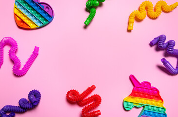 Colorful antistress children toys on pink paper with copy space