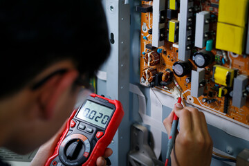 Hand of a mechanic using electrical measuring tools to repair electronic circuits Professional maintenance technician concept.