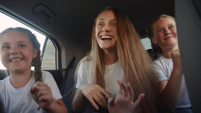 children teenagers dancing in the car on the road travel. happy family adventure a kid dream concept. friendly family sisters dancing having fun to the music in the car fun on the way to vacation