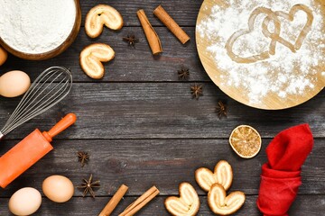 Valentine's Day baking culinary background. Ingredients for cooking -whisk, eggs, cinnamon sticks, star anise, flour, napkin on wooden kitchen table. Baking recipe for pastry. 