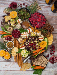 Luxurious cheese board consisting of cheese balls with a variety of crackers, pretzels and crudites, fruit, top view