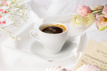 Serene coffee break moment with a rich, steaming cup, complemented by pastel floral blossoms and a subtle note in the background, encapsulating a personal touch.