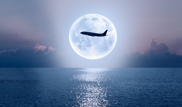 Silhouette of a passenger plane passing in front of the full moon "Elements of this image furnished by NASA "