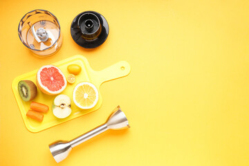 Hand blender and accessories with sliced fruit on a yellow background, space for text. Top view.