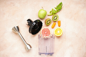 Hand blender and accessories with sliced fruit on a beige background. Top view.